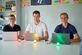 drei Studierende vor ihren Laptops mit je einer roten, gelben und grünen LED-Lampe