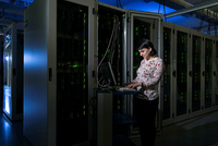 Wissenschaftlerin vor einer Wand voller Server