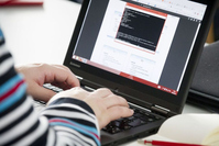 Hände einer Person tippen auf einem Laptop.